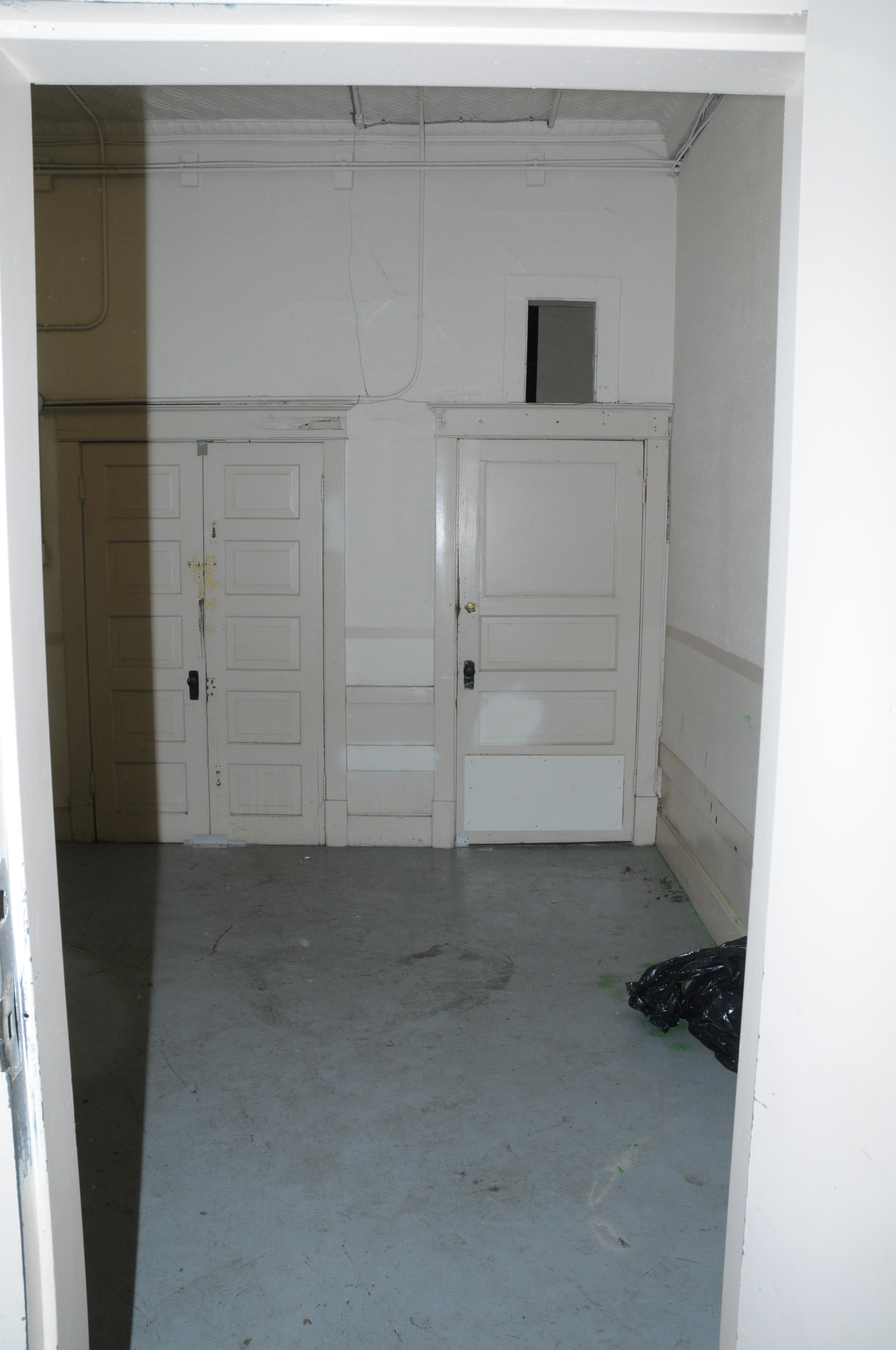 Traveler's Block laundry room, de-commissioned elevator shaft to the left, and a locked door to the right with a transom window above.